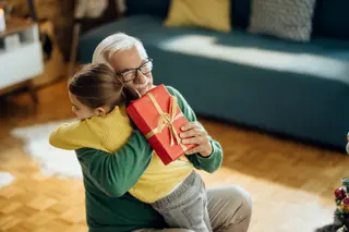 Grateful little girl embracing her grandfather while giving him a present

