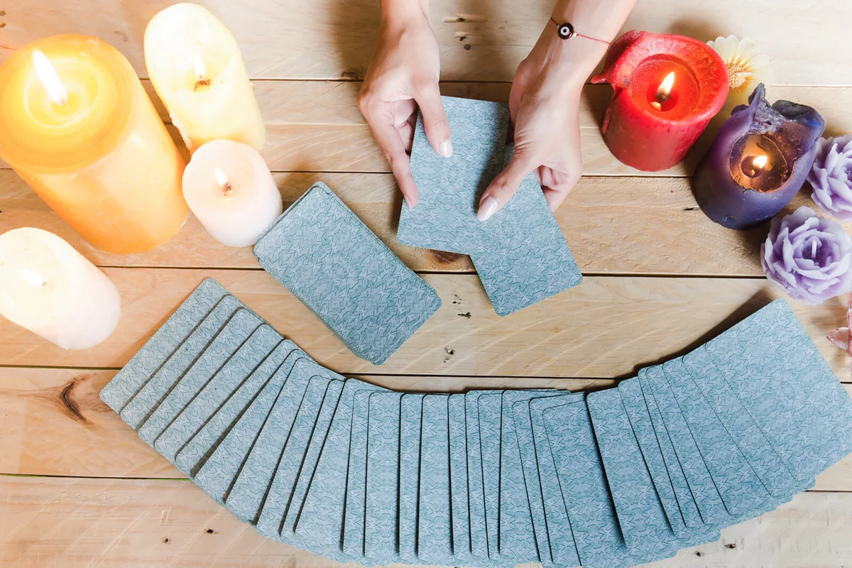 Fortune teller female hands and tarot cards on wooden table